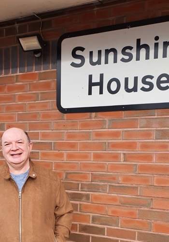 man standing next to a sign that says Sunshine House