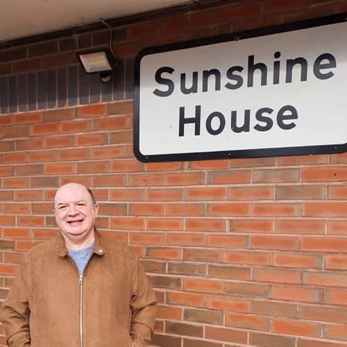 man standing next to a sign that says Sunshine House