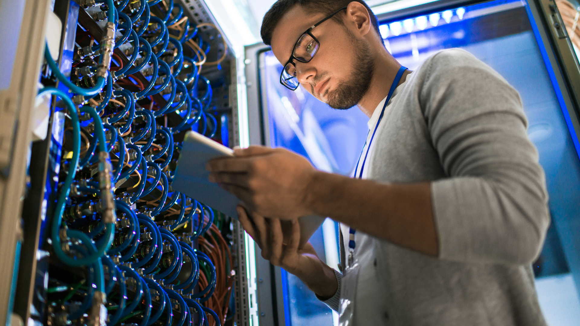 Man on an iPad looking standing at an electrical hub