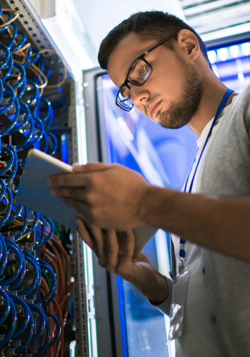 Man on an iPad looking standing at an electrical hub