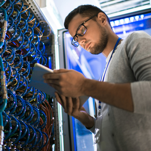 Man on an iPad looking standing at an electrical hub