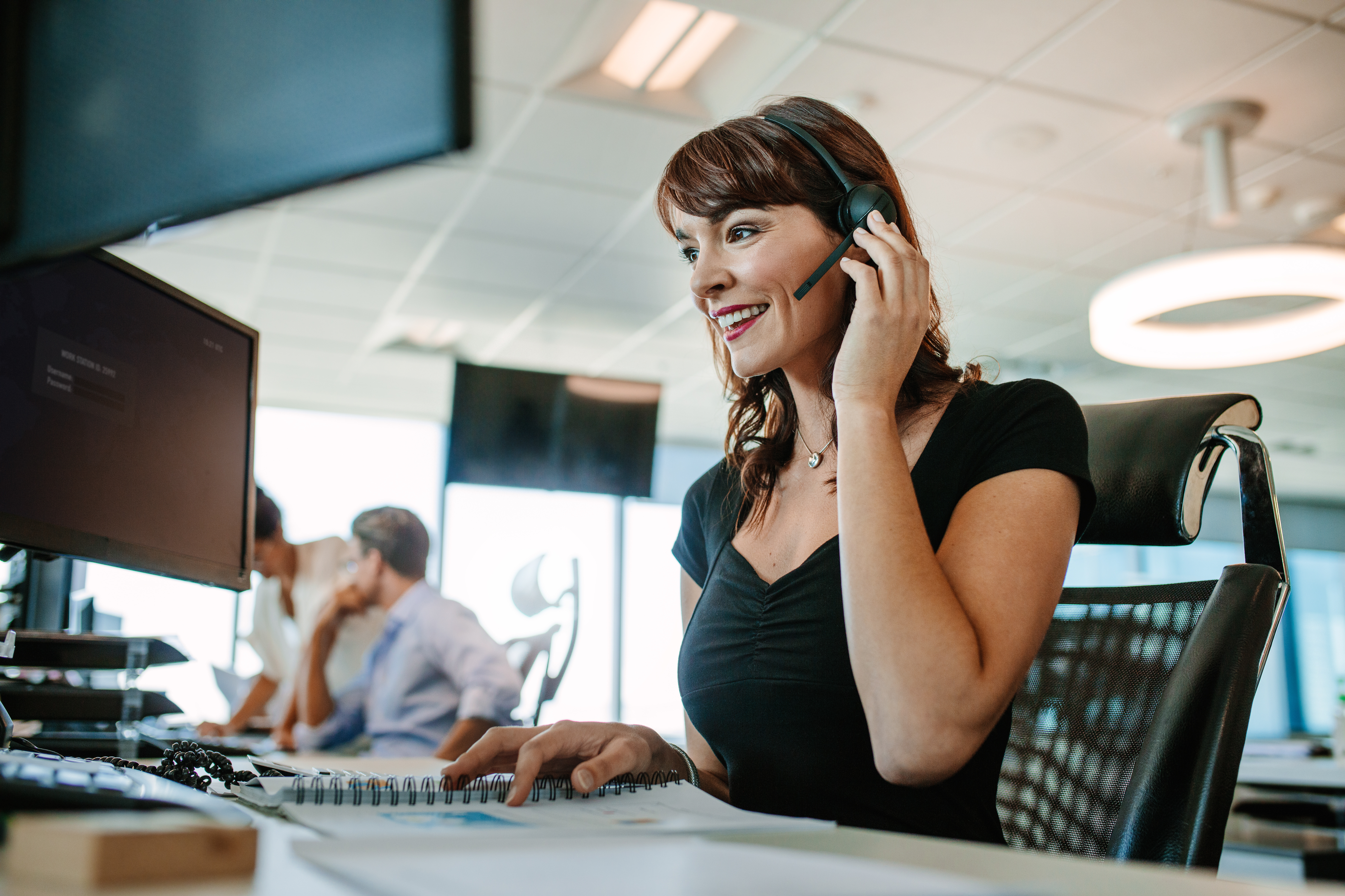 Woman in an office on a computer with a headset 