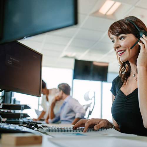 Woman in an office on a computer with a headset 